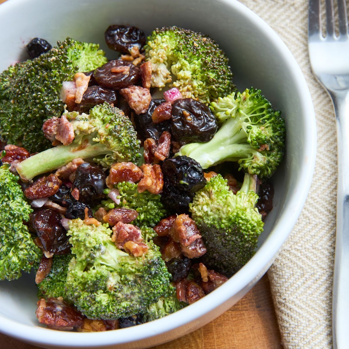 Close up of bacon and broccoli salad in bowl with fork