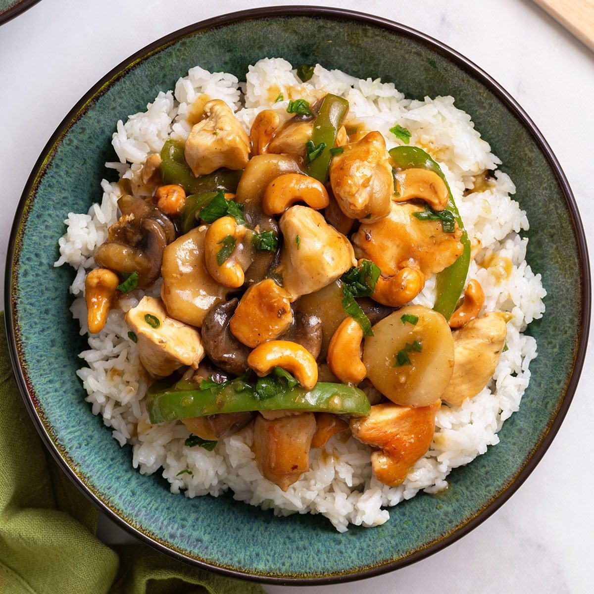 Overhead view of Cashew Chicken stir fry on top of hot rice in a serving bowl for Cashew Chicken recipe for Taste of Home